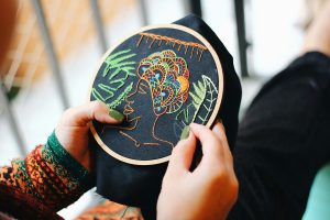 Hands doing simple counted cross stitch in a hoop