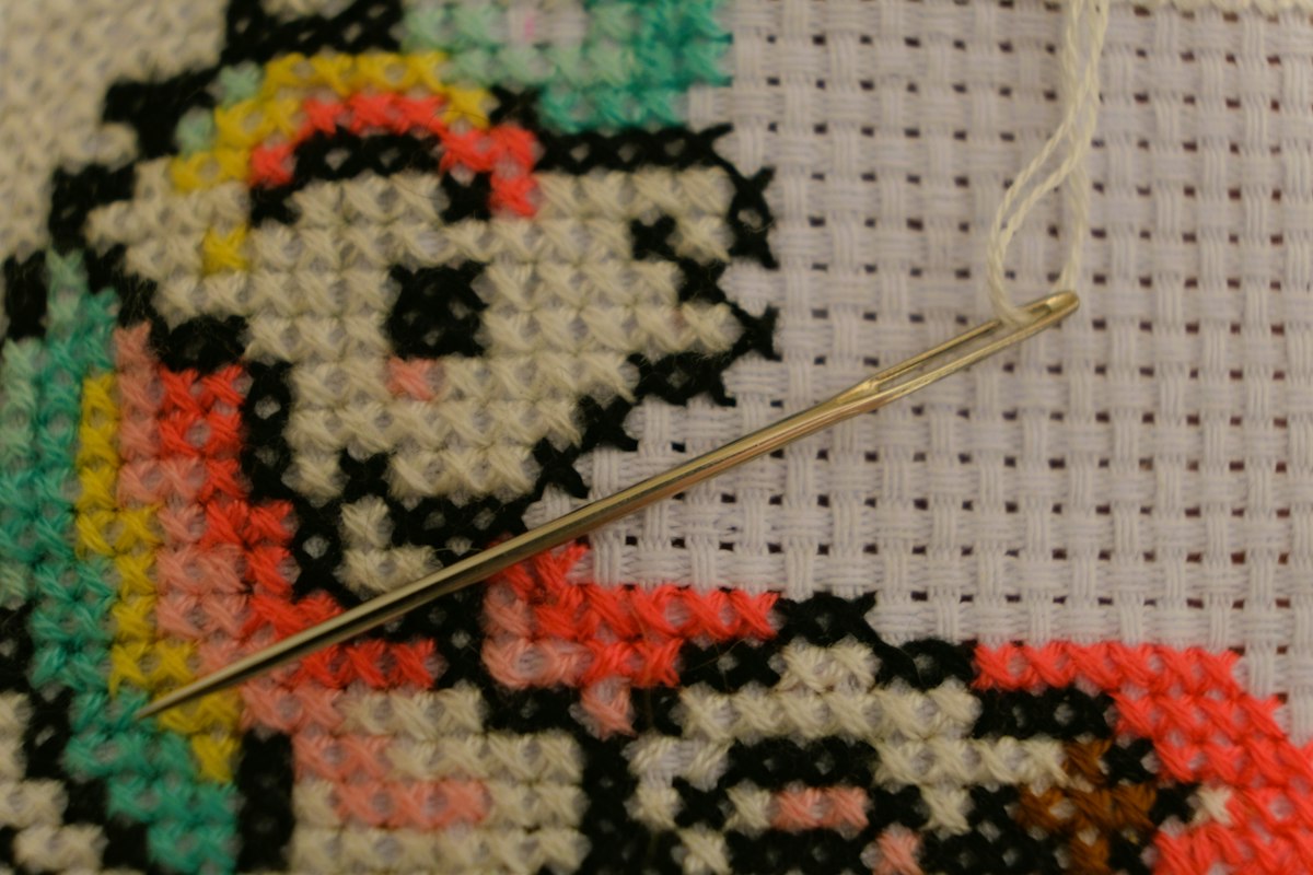 Free Cross Stitch Charts: Rain Cloud and Teacup Motifs Modern Cross Stitch Patterns & PDF Charts | XStitchPattern Needle resting across colorful cross stitches and the open grid of white Aida