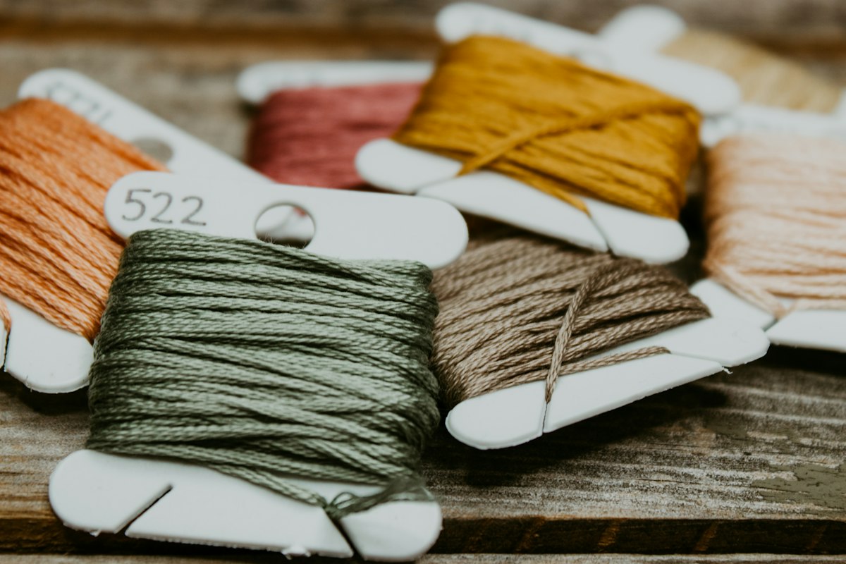Embroidery floss wound on bobbins in green, tan, mustard and muted pink