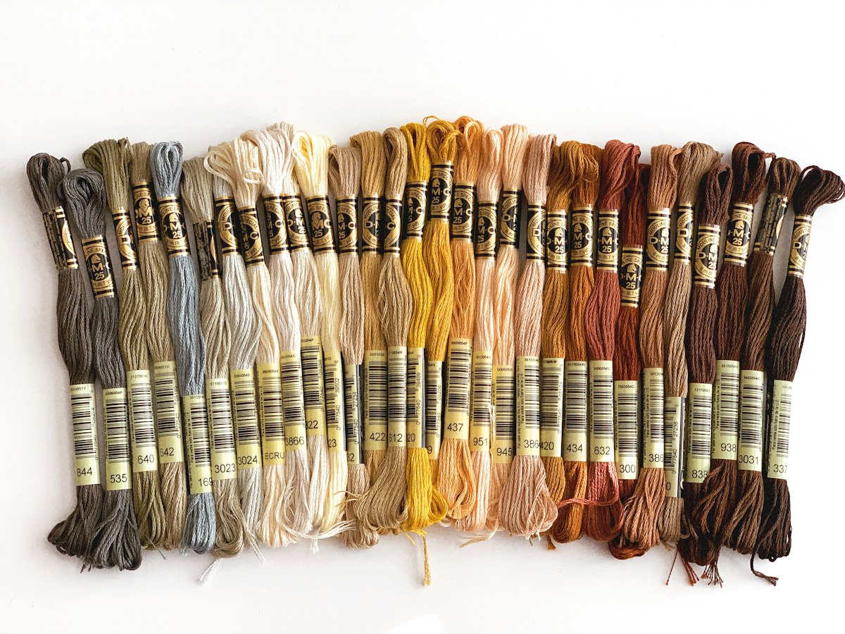 Stranded cotton embroidery skeins arranged from gray and cream to gold and brown