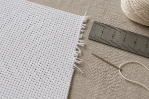 Frayed Aida edge beside a ruler showing the intact fabric margin